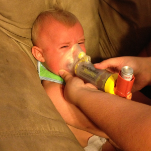 An infant breathes from an inhaler after suffering respiratory problems following a tar sands pipeline accident in Mayflower, Arkansas. By Genieve Long