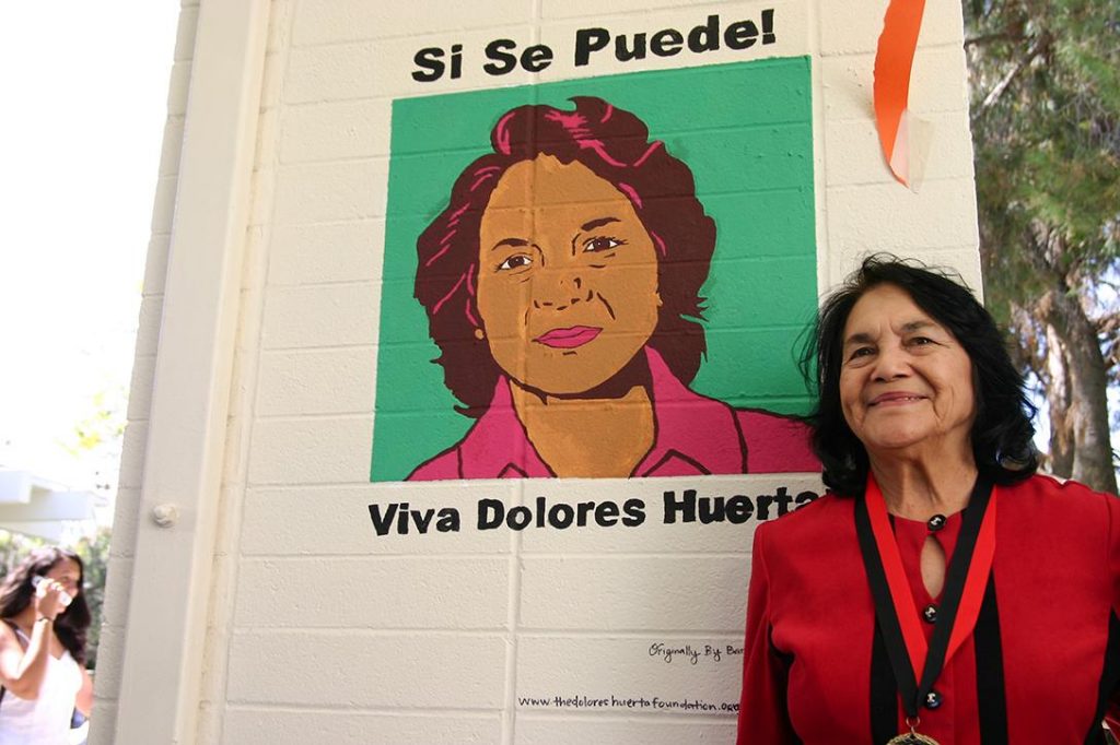 Dolores Huerta in front of student mural painted by Kimberly Bautista. 