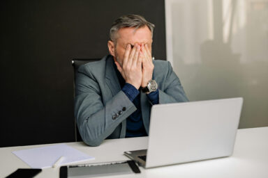 Frustrated man, covering face, laptop