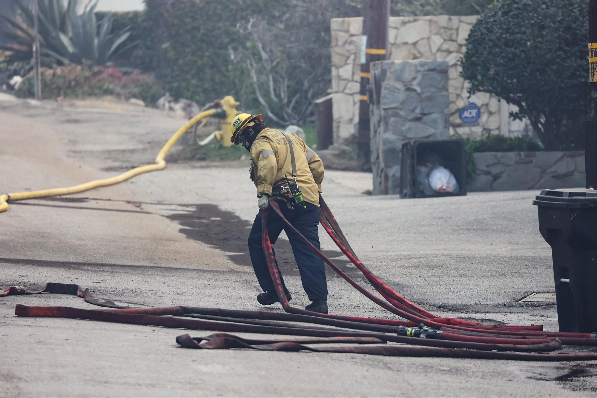 Firefighters, pulling hoses, Pacific Palisades Fire