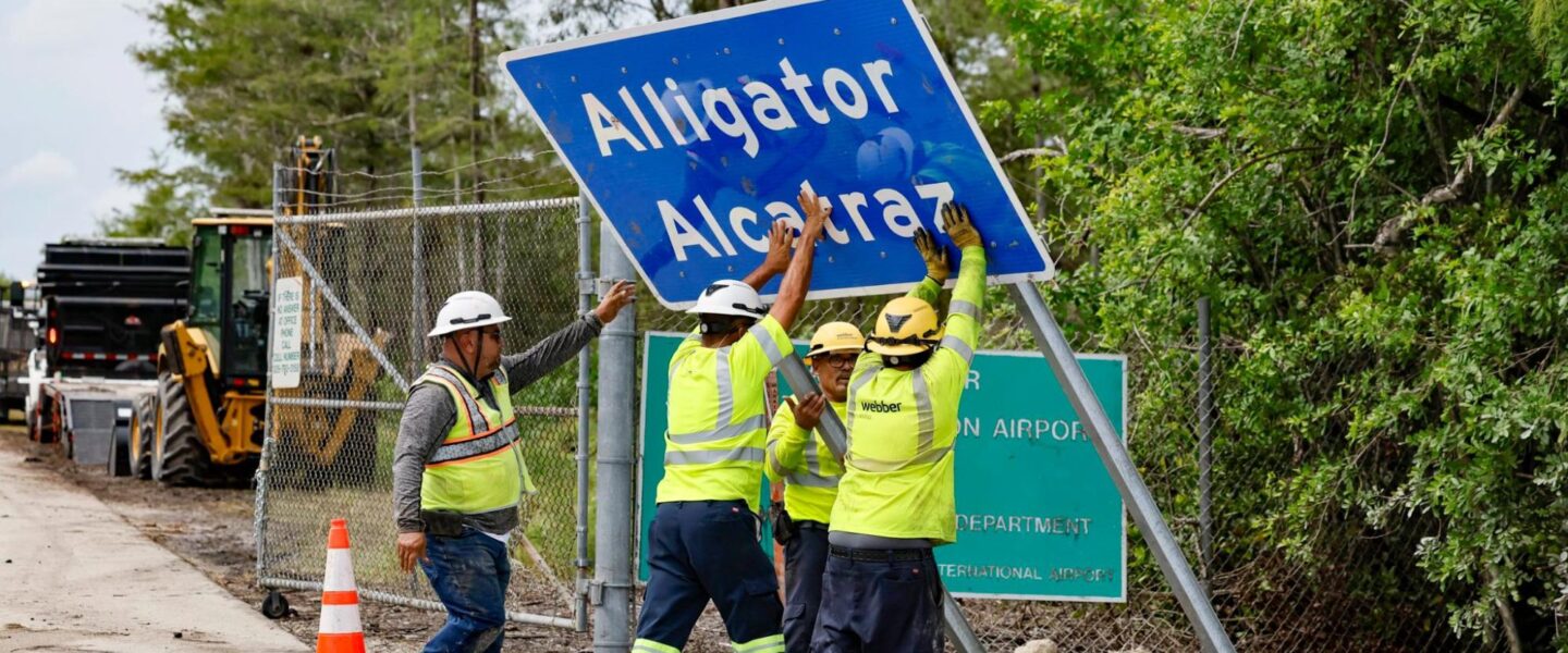 Workers, install, Alligator Alcatraz, sign