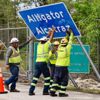 Workers, install, Alligator Alcatraz, sign